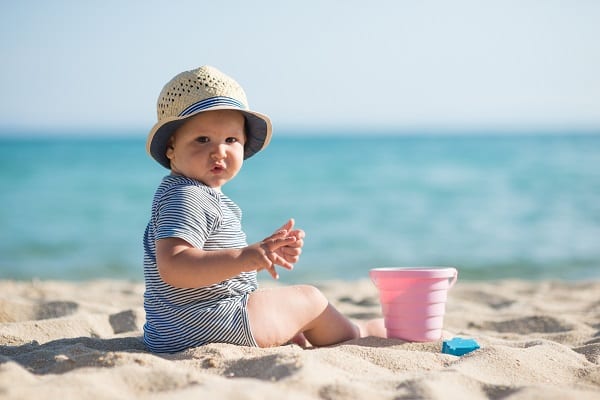 Toddler with sandcastles on the beach